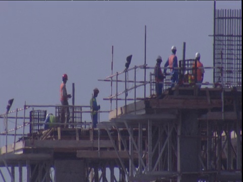 人们在迪拜建筑工地的脚手架塔顶上工作视频素材