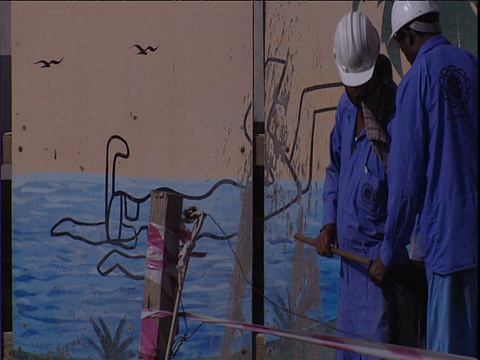 工人在蓝色工装裤走过建筑工地收集垃圾迪拜视频素材