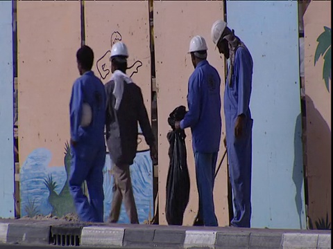 建筑工人在蓝色工作服走在建筑工地前收集垃圾迪拜视频下载