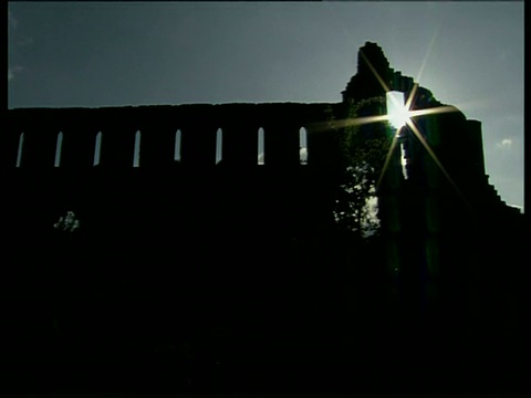 落日的余辉映衬着天空，修道院废墟的黑暗墙壁的轮廓。Jervaulx修道院。视频素材