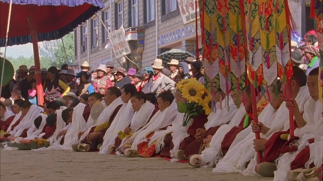 潘在游行中穿过一排举着经幡的僧侣。视频素材