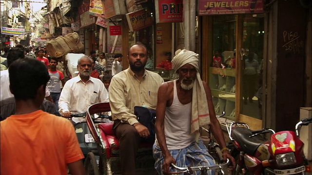 在新德里，人们沿着一条繁忙的街道行走。高清。视频素材