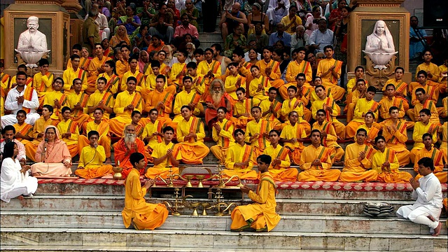 身穿橙色长袍的信徒们在恒河的台阶上摇摆、拍手。高清。视频下载