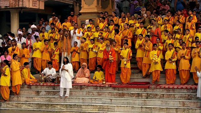 身穿橙色长袍的信徒们在恒河岸边拍手、吟唱。高清。视频下载