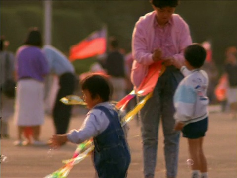 亚洲，穿着蓝色工装裤的小男孩跑来跑去追逐泡沫。视频下载