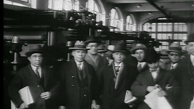 1927年，一群戴着帽子拿着报纸的男人站在报社/新闻片里视频素材