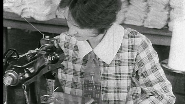 20世纪20年代在服装厂的缝纫机上近距离缝制衣领的妇女/新闻片视频素材
