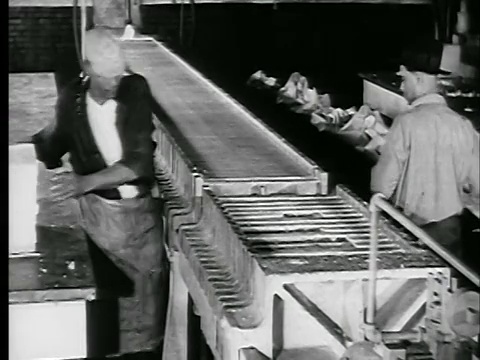 1929年高角度两个男人从工厂/新闻胶片架上取下蜡片视频素材