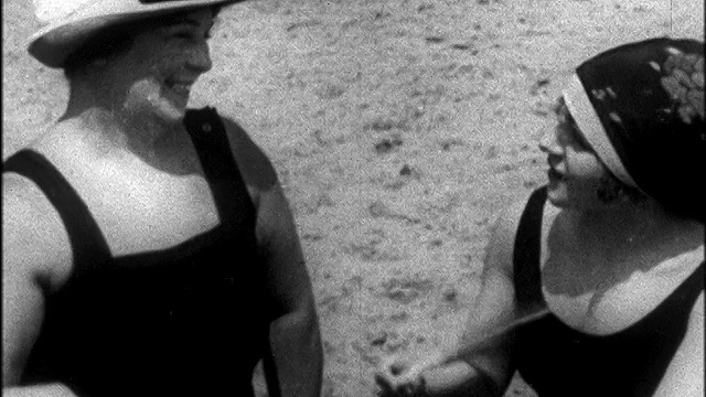 1925年B/W特写中年+年轻女子在泳装+帽子挥舞扇子在海滩/新闻胶片视频下载
