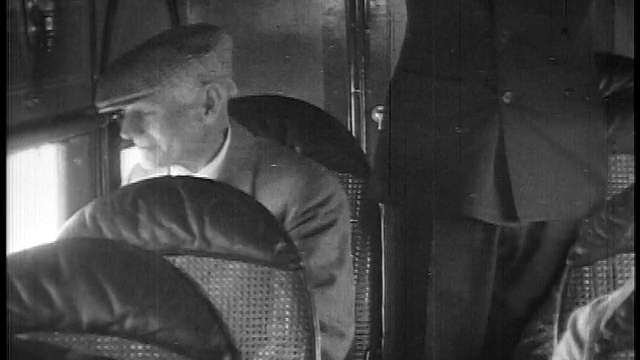 1927年近距离拍摄戴帽子的老人坐在飞机上看窗外/新闻短片视频素材