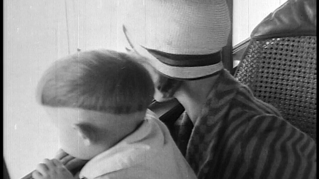 1927年近距离的母亲戴着钟形帽+男孩坐在飞机上看着窗外/新闻短片视频素材