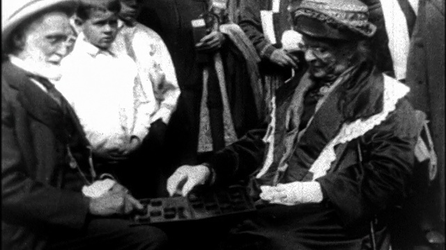 1927年，一对老年夫妇在老年大会上下棋，其他人在背景观看/新闻短片视频素材
