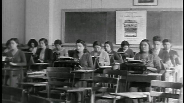 B/W 20世纪20年代的一群美国原住民学生坐在学校/教育室的书桌前，旁边放着打字机视频下载