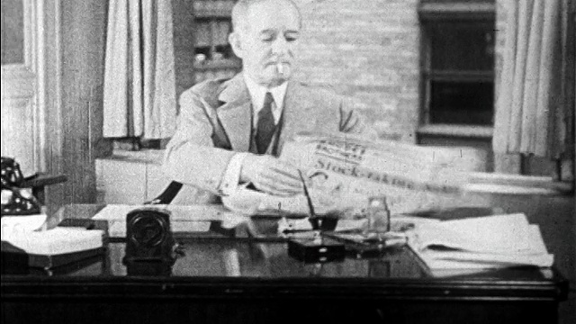 1929年中年商人坐在桌前看报纸+抽烟/看新闻短片视频素材