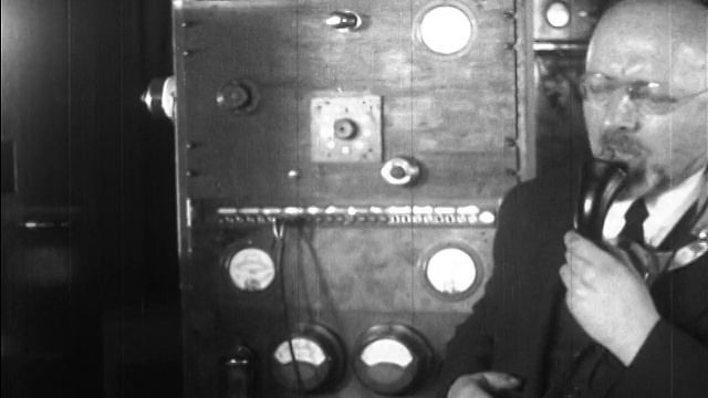 1927年，一名戴眼镜、蓄胡须、戴耳机的男子对着麦克风测试实验电视视频素材