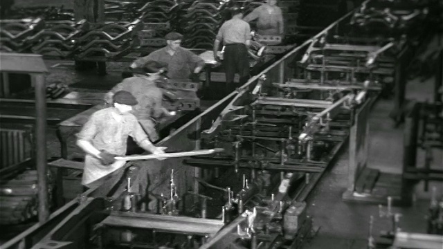 1936年在雪佛兰汽车厂，一群在输送带上工作的高角度工人视频素材