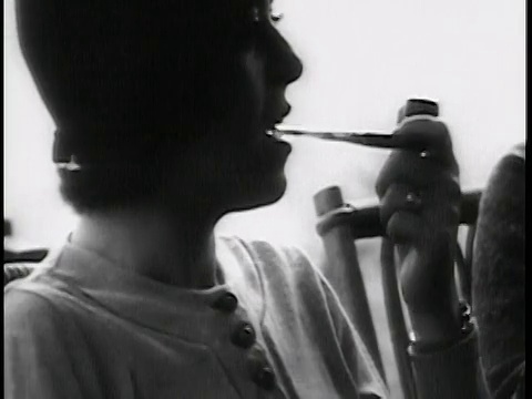 1938年B/W特写:戴帽的妇女坐着+抽烟斗/新闻短片视频素材