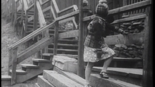 1939年的女孩靠在栏杆上，看着2个孩子从她身边走过视频素材