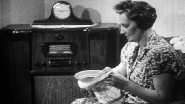 20世纪30年代的中年妇女坐着，一边听收音机一边晒盘子/教育视频素材