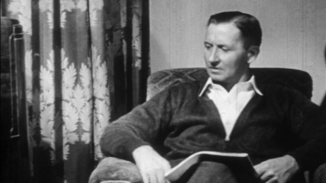 20世纪30年代的中年男子坐在扶手椅上，手里拿着杂志视频素材