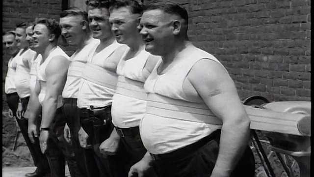 1935年，一队穿着背心的警察站在那里，腹部带着振动的带子视频下载