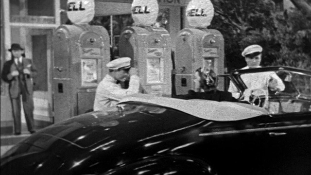 1939年，加油站工作人员向坐在敞篷车/壳牌石油加油机中的妇女脱帽致意视频下载