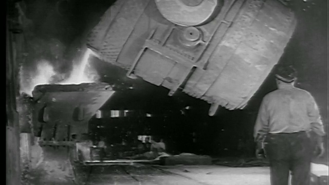 B/W 1942/43在工厂倾倒钢水的机器/工厂工人站在前景/新闻胶片视频素材