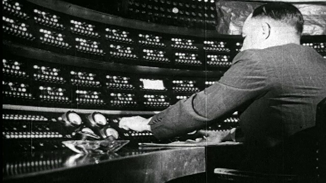 1938年后视镜男子坐在广播演播室操作控制面板/新闻胶片视频下载