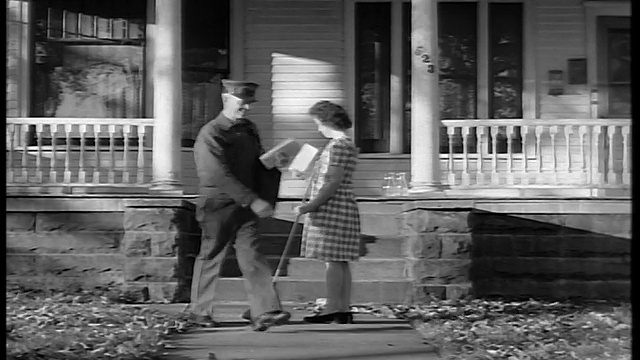 1944年，一名黑人和白人邮递员把邮件递给在屋前清扫人行道的妇女视频素材