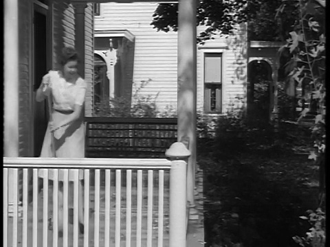 1944年，一名黑人和白人妇女在清扫房屋的门廊，并与屏幕外/纪录片中的某人交谈视频素材