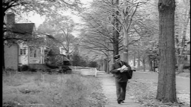 1943/44年，邮递员走在郊区的人行道上看邮件/新泽西斯普林菲尔德/新闻短片视频素材