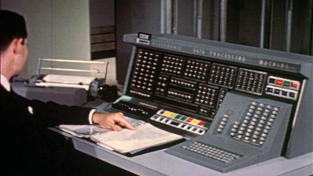 20世纪50年代，一名身穿深色西装的男子在IBM 705电脑控制台按按钮视频素材