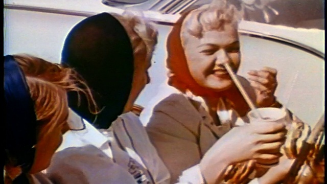 1958年，三个头上戴着头巾的少女在免下车的敞篷车里吃汉堡视频素材