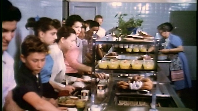 20世纪50年代的儿童/青少年在学校餐厅吃东西/倾斜到男孩的手付款+托盘视频下载