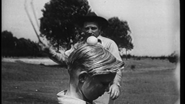 1951年B/W慢动作男子用鞭子从男孩的头顶抽打球/新闻短片视频下载