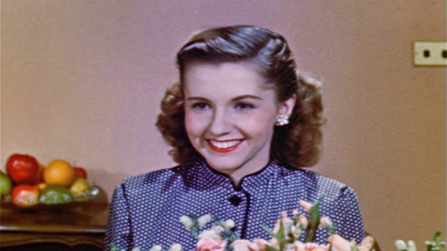 1952年近距离的少女坐在插花后面看着屏幕外的某人+微笑/工业。视频素材