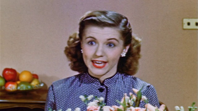 1952年，近距离的少女坐在花后面和屏幕外的人说话视频素材