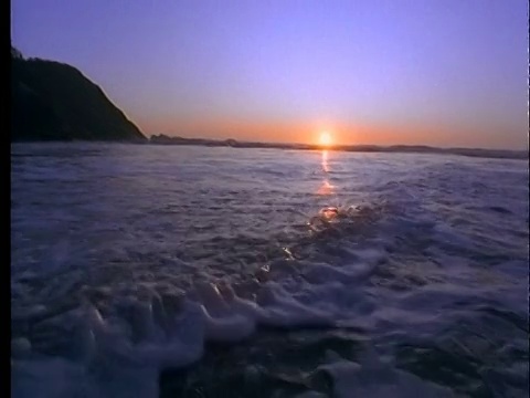 日落时后退的海浪的低视角视频素材