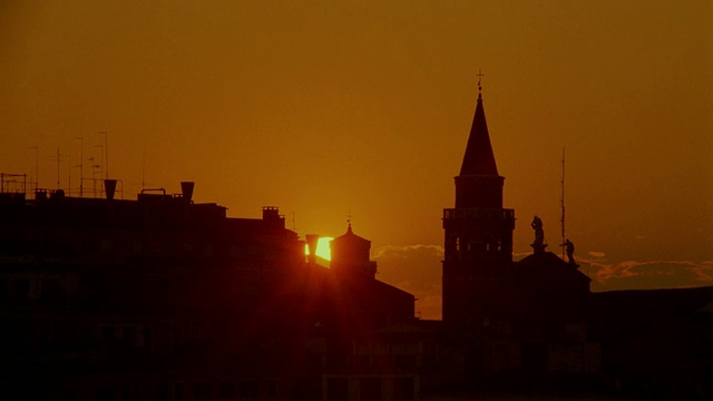 日落在橙色的天空后面的建筑物剪影/威尼斯视频下载