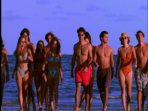 一群穿着泳衣的人在海滩上朝着cam走去视频素材