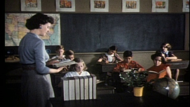 1960年的老师在教室前朗读和和孩子们交谈/女孩举起了手视频下载