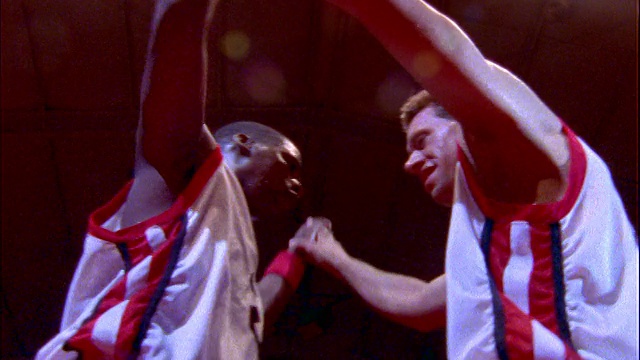 慢镜头低角度白+黑篮球运动员在室内球场互相击掌视频素材