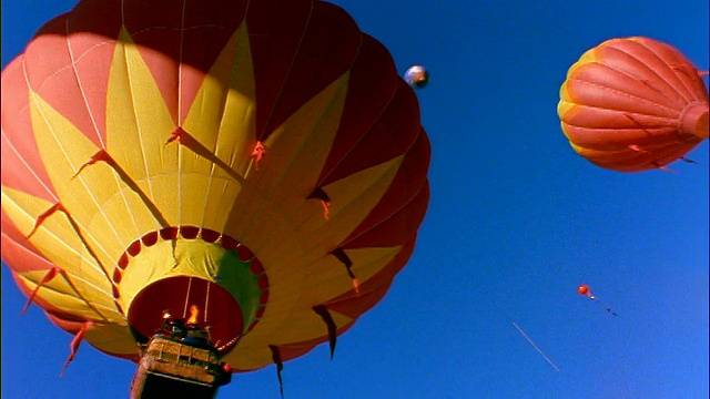 低角度PAN色彩鲜艳的热气球在清澈的蓝色天空中飞行/斯诺马斯，科罗拉多州视频素材