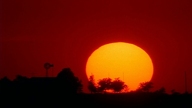 时间流逝巨大的太阳落在橙色的天空后面的剪影德州农场/橙色滤镜视频素材