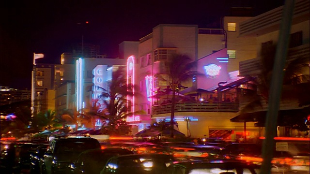 时间流逝的交通+人们在城市街道上的装饰艺术建筑前的夜晚/迈阿密海滩视频素材