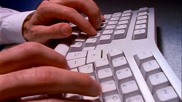 慢镜头近距离跟踪拍摄商人的手在弯曲的电脑键盘上打字视频素材