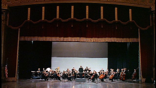 在音乐厅里，宽大的幕布在管弦乐队上空落下视频下载