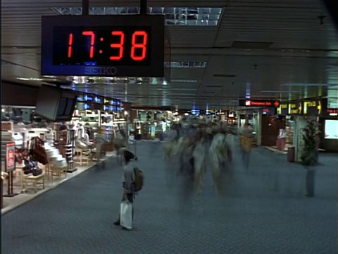 时间流逝的人在机场航站楼/数字时钟在前景视频下载