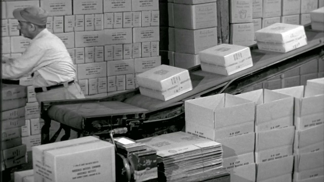 1950年工人在工厂把箱子放到传送带上视频素材