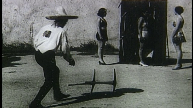 20世纪20年代/30年代的慢动作，戴着宽边帽的男子向穿比基尼的女子投掷十字镐视频下载